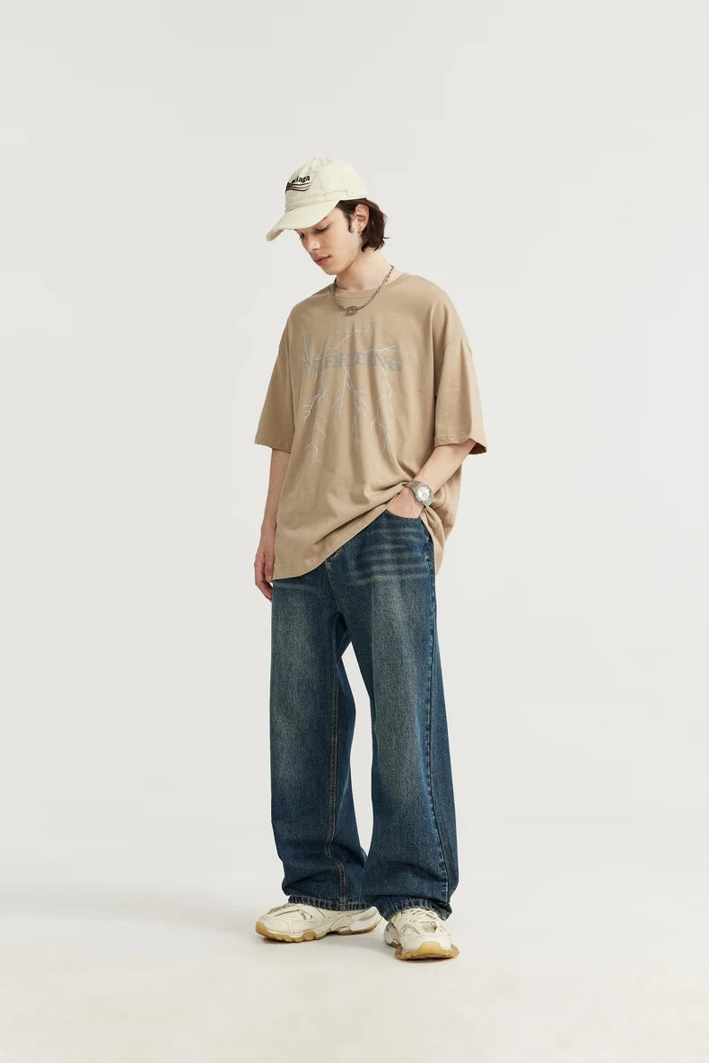 Model wearing the blue Washed Vintage Loose Jeans in a gray background 