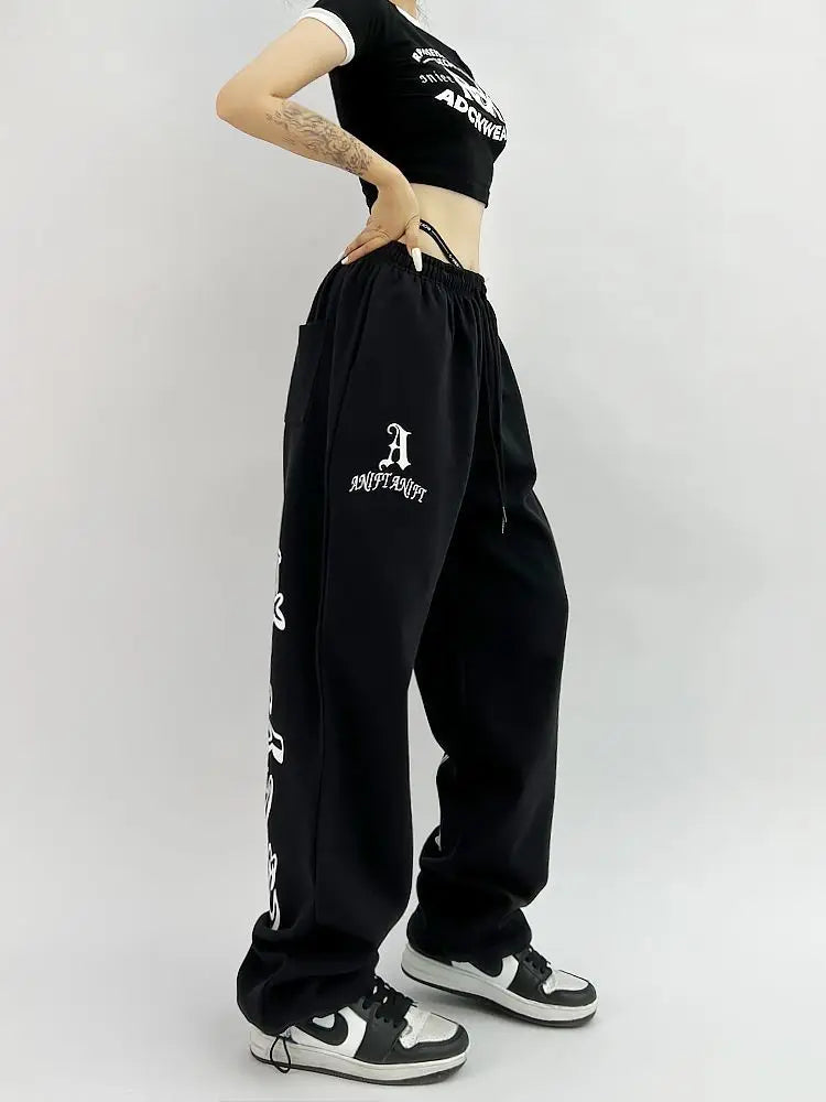 Model wearing the black Y2K Loose Graphic Sweatpants in a gray background