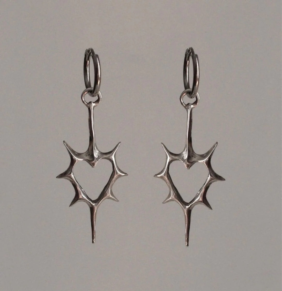 Front view of the heart Stellar Edge Earrings in a gray background