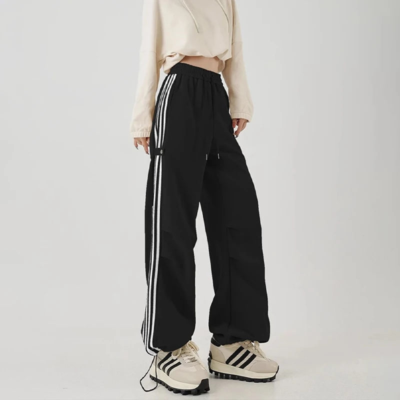 Model wearng the black Wide-Leg Track Pants in a gray background